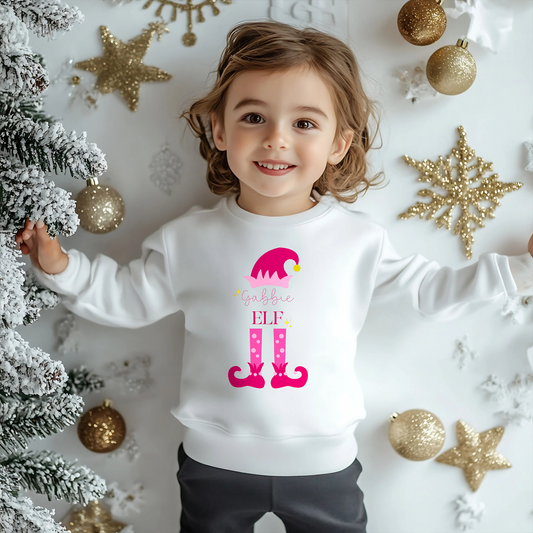 Personalised christmas elf sweatshirt: A pink sweatshirt featuring a cute elf design. It’s personalised with a child's name, adding a special touch to the festive season. Made from soft, high-quality materials for comfort and warmth. Ideal for Christmas gatherings and events, particularly Christmas jumper day