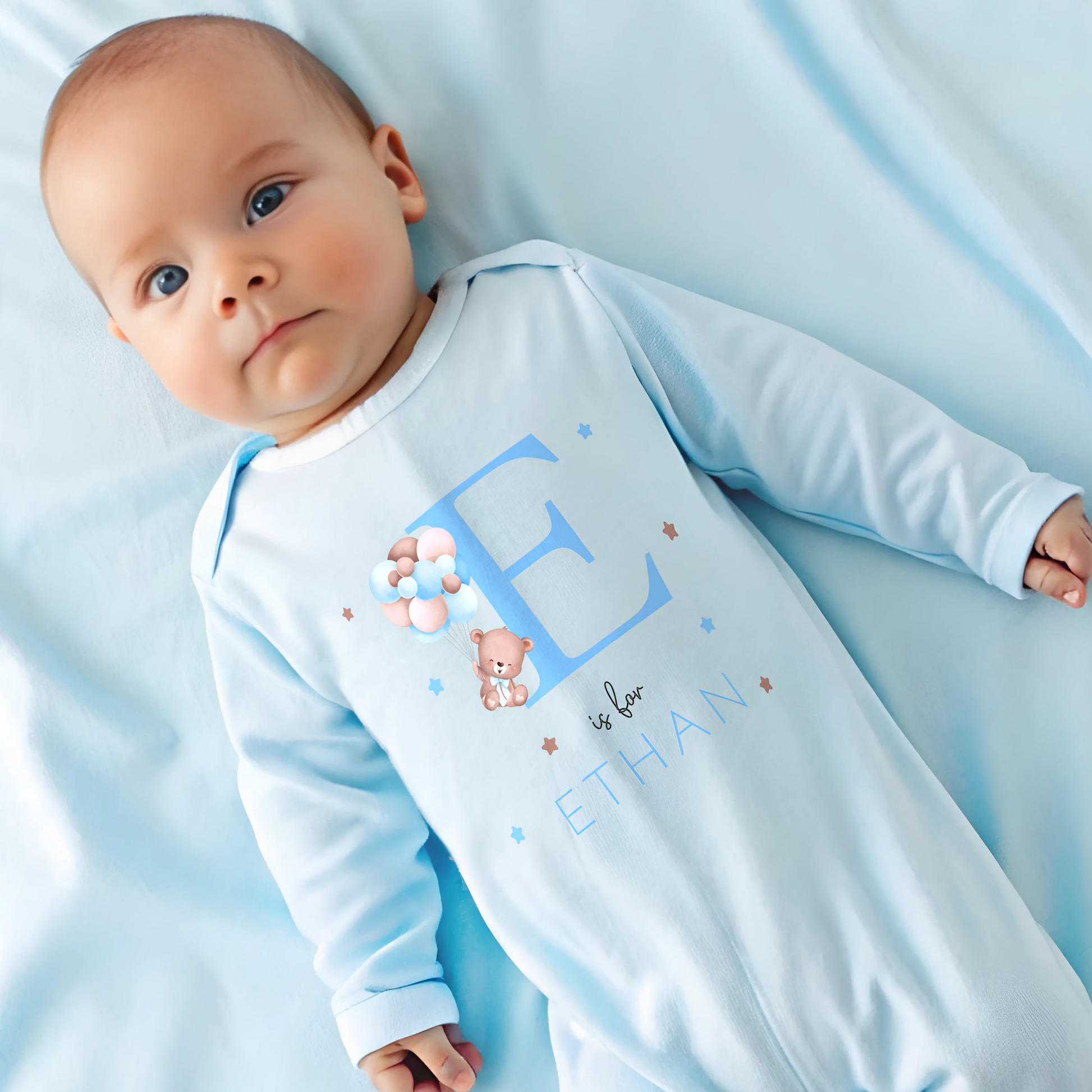 personalised baby outfit: A personalised baby boy outfit featuring a blue balloon bear design with baby name initial. Available as a sleepsuit, bodysuit, T-shirt, or bib, this charming new baby gift is perfect for a coming home outfit or gender reveal celebration.