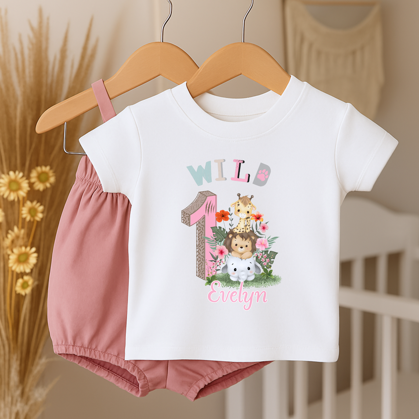 Wild One birthday t-shirt: A personalised Wild One 1st Birthday T-shirt for girls, featuring charming safari animals and vibrant colours. The shirt, designed for a jungle safari theme birthdays, includes space to customise with your child's name. Made from soft, high-quality materials, it promises comfort and style for your baby's first birthday celebration.