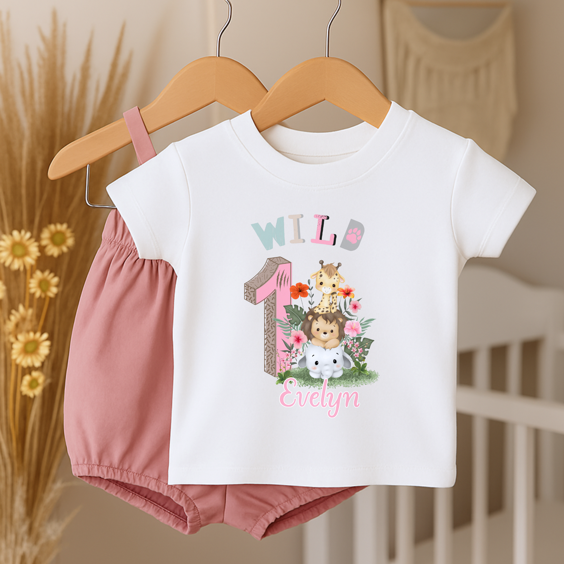 Wild One birthday t-shirt: A personalised Wild One 1st Birthday T-shirt for girls, featuring charming safari animals and vibrant colours. The shirt, designed for a jungle safari theme birthdays, includes space to customise with your child's name. Made from soft, high-quality materials, it promises comfort and style for your baby's first birthday celebration.