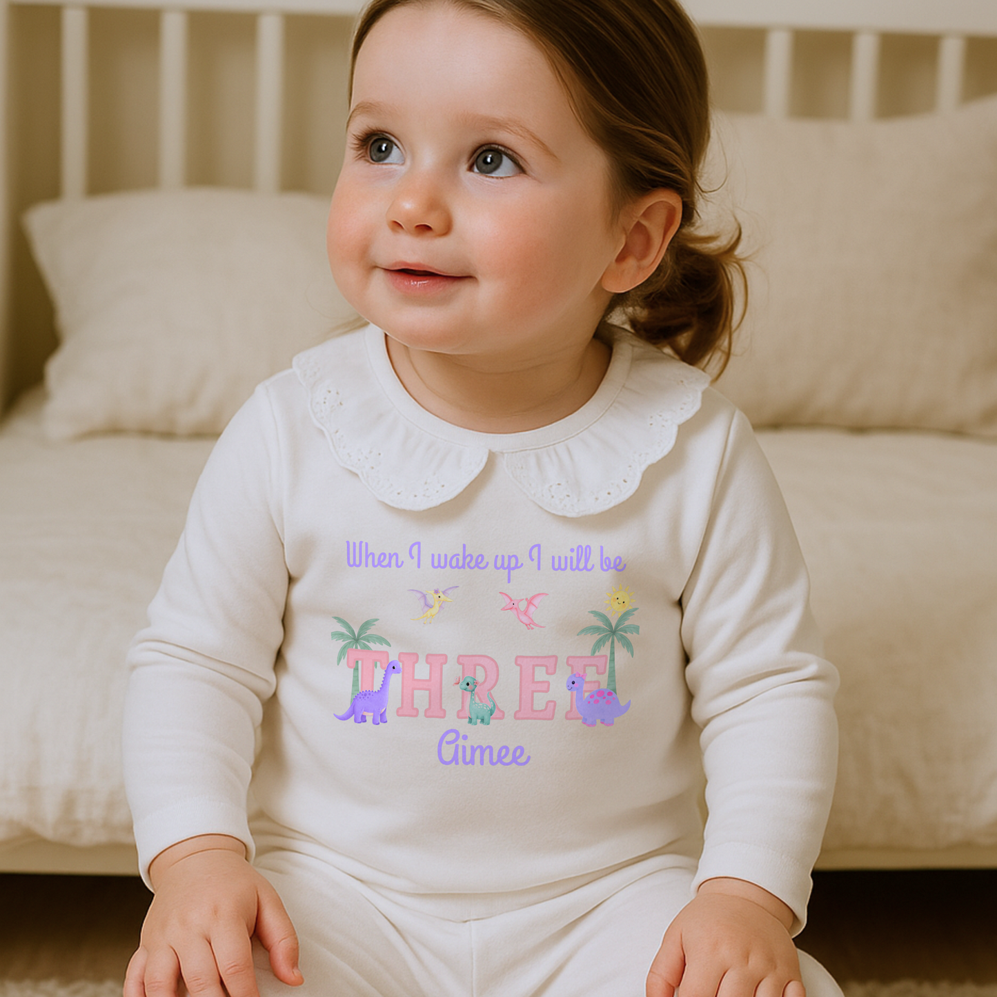 Girls dinosaur birthday pyjamas personalised with name and age featuring pastel dinosaurs and palm trees with custom name
