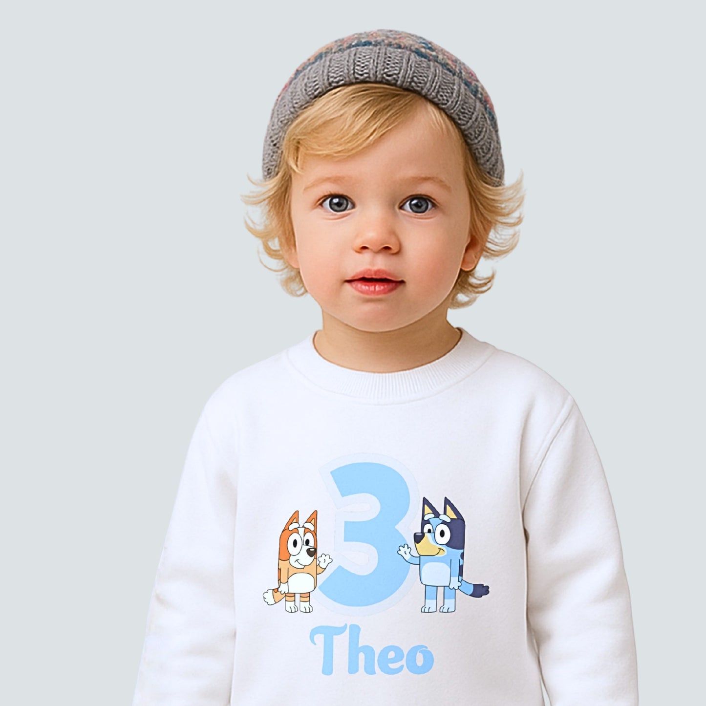 Boys personalised Bluey and Bingo birthday sweatshirt with custom name and age worn by young child.