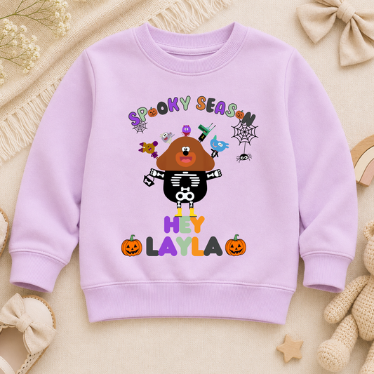 Flat lay of personalised Halloween sweatshirt with trick-or-treat, Spooky Season design and custom name custom name