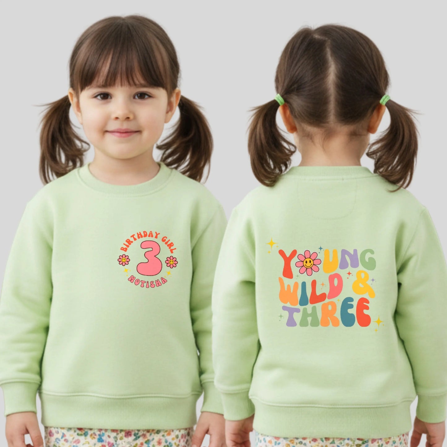 Girls Young Wild and Three birthday sweatshirt in groovy retro style, featuring birthday girl text, retro emojis, a personalised name on the front and bold nostalgic graphics on the back