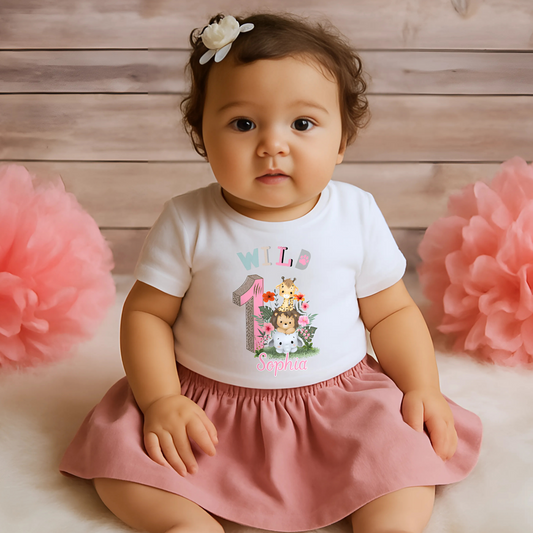 Wild One birthday t-shirt: A personalised Wild One 1st Birthday T-shirt for girls, featuring charming safari animals and vibrant colours. The shirt, designed for a jungle safari theme birthdays, includes space to customise with your child's name. Made from soft, high-quality materials, it promises comfort and style for your baby's first birthday celebration.