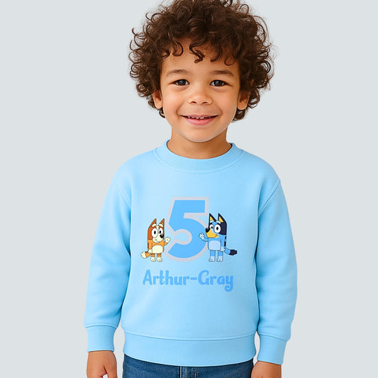 Boys personalised Bluey and Bingo birthday sweatshirt with custom name and age worn by young child.