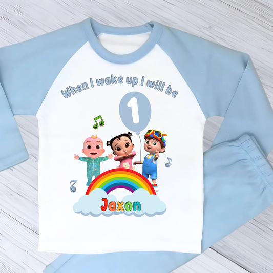 Cocomelon birthday pyjamas for boys with custom name and age, rainbow design with favourite Cocomelon characters, birthday number in blue balloon, and name printed under fluffy clouds, soft and comfy sleepwear set for birthday mornings