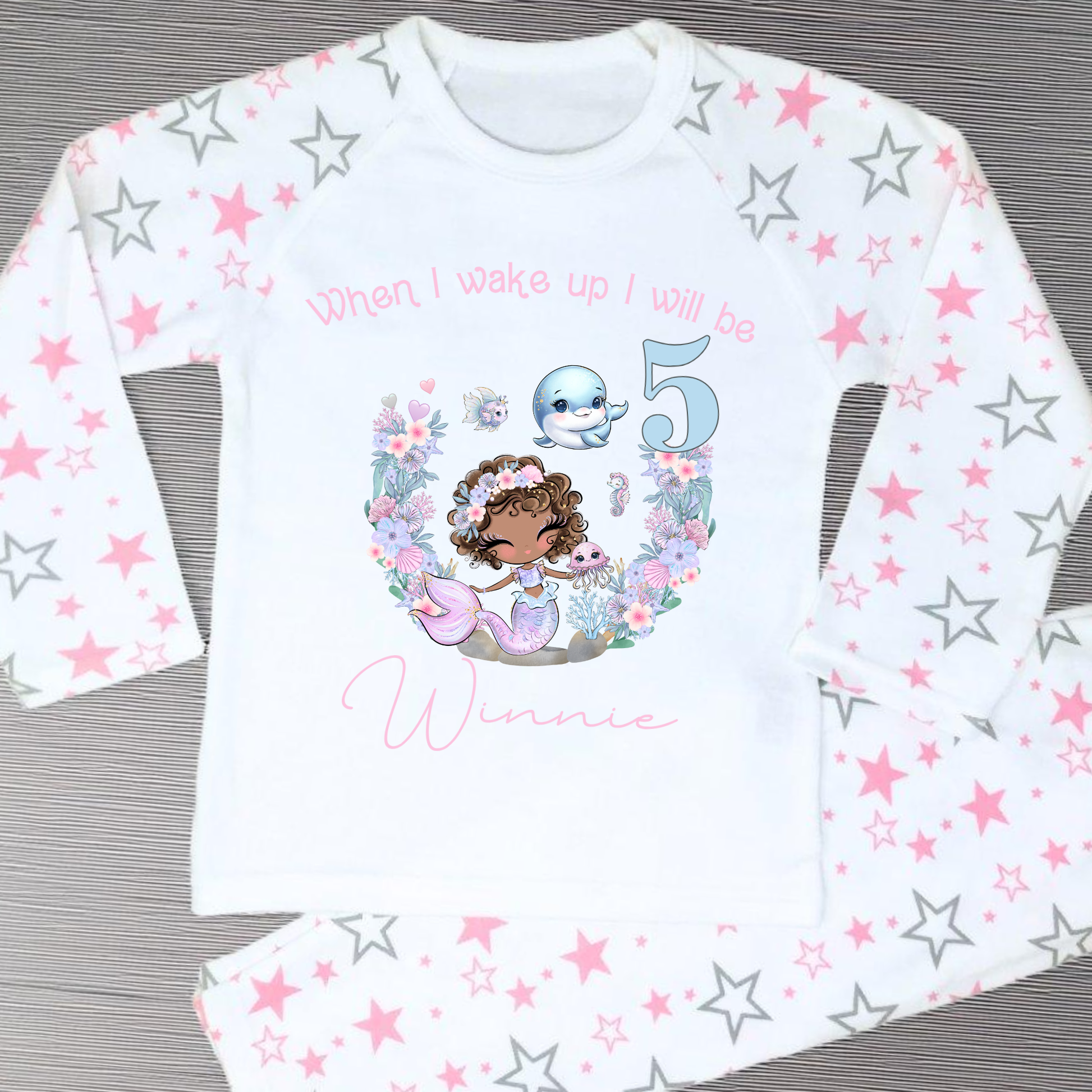 Mermaid birthday pyjamas, personalised for girls: A pair of mermaid birthday pyjamas in lilac and pink, featuring a glitter-like design. The top displays the phrase “When I Wake Up I Will be,” personalized with a girl's name and age. Ideal for young mermaid enthusiasts, these Pyjamas make a magical birthday gift for girls, when i wake up mermaid