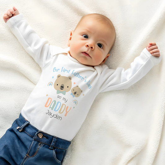 First Father's Day Outfit: A baby dressed in a personalized First Father’s Day outfit. This unique gift for new dads includes a choice of a sleepsuit, vest, T-shirt, or bib, all featuring a charming design. At the top, it reads “First Father’s Day as My Daddy,” accompanied by an adorable illustration of a baby bear and a father bear, along with the child’s name.