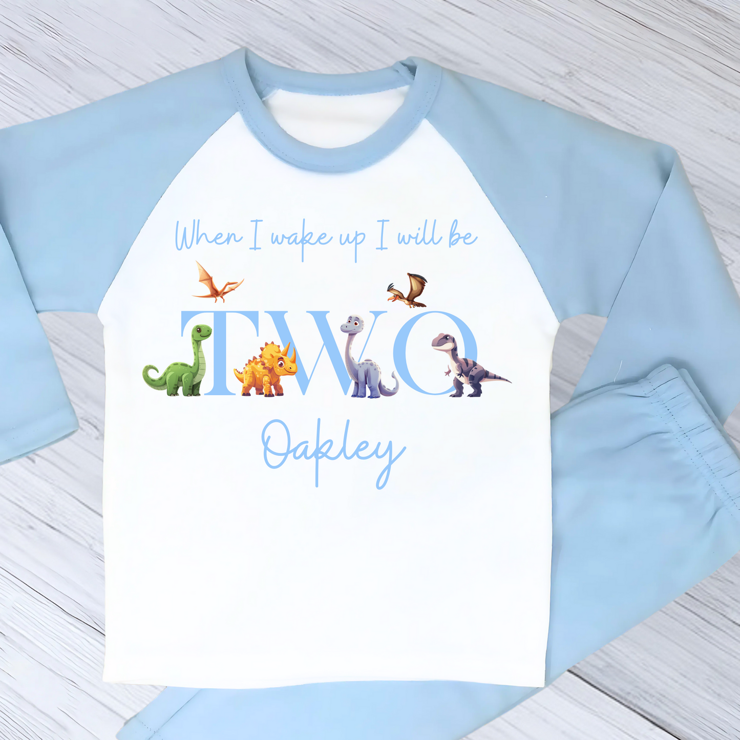 Dinosaur Birthday Pyjamas: A pair of toddler boys pyjamas with a dinosaur theme is displayed. The design features the phrase “When I Wake Up" accompanied by vibrant dinosaur graphics and the child's age. These two-piece pyjamas can be personalised with the boys name and age, creating a unique birthday outfit. Ideal for young dinosaur enthusiasts, these playful and colorful jammies make bedtime exciting and birthday mornings special.