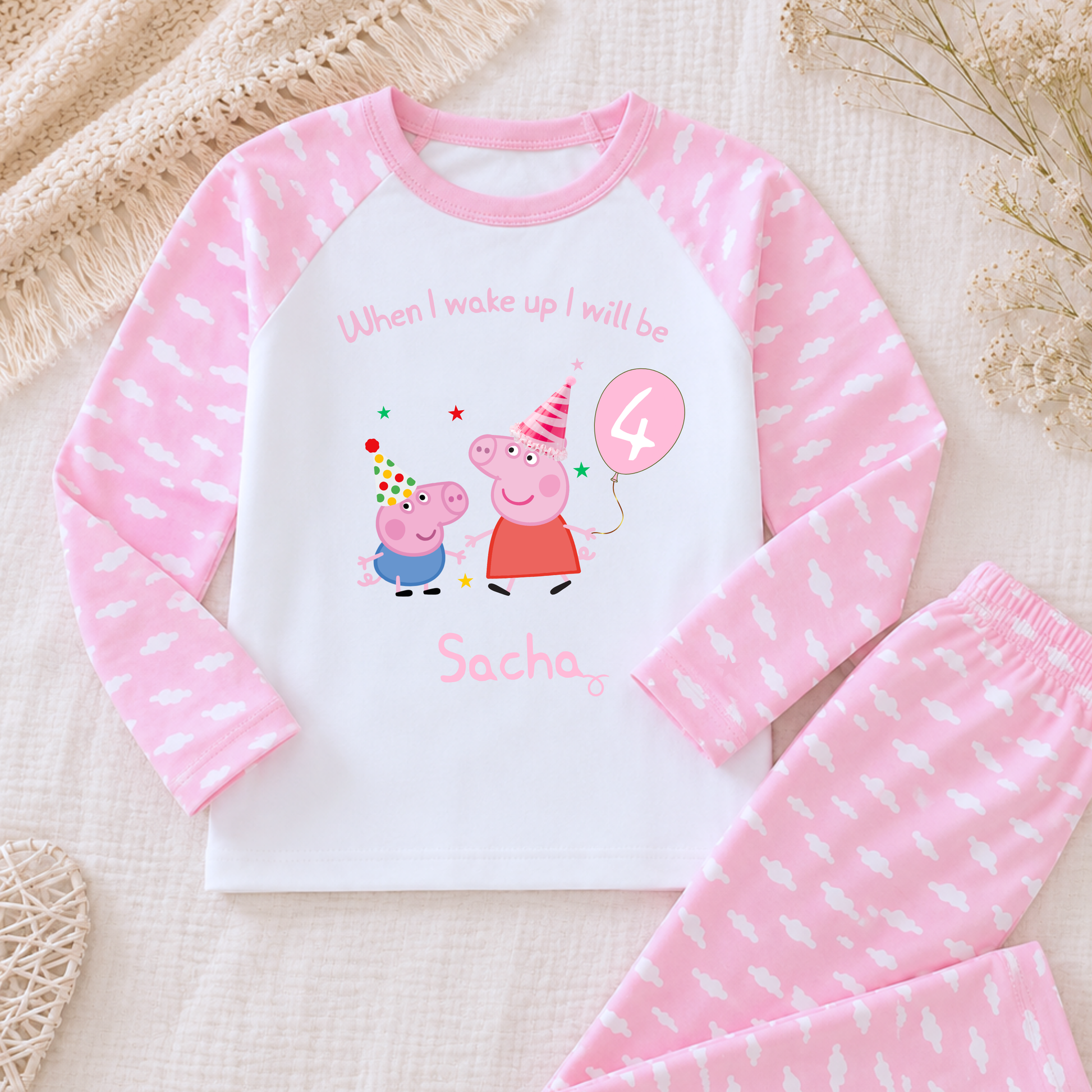 Girls Personalised Peppa and George Pig Birthday Pyjamas, Peppa Pig Personalised Pyjamas, When I wake Up I'll Be Pj's, Girls Peppa Pig Pjs, Peppa Pig Birthday Gift, Name Pyjamas, Happy Birthday Pjs, A children's two-piece pajama set laid flat on a textured cream fabric background. The long-sleeve top is white with pink sleeves and a pink pattern, featuring a Peppa Pig birthday graphic with the text 'When I wake up I will be Sacha' and a '4' balloon.