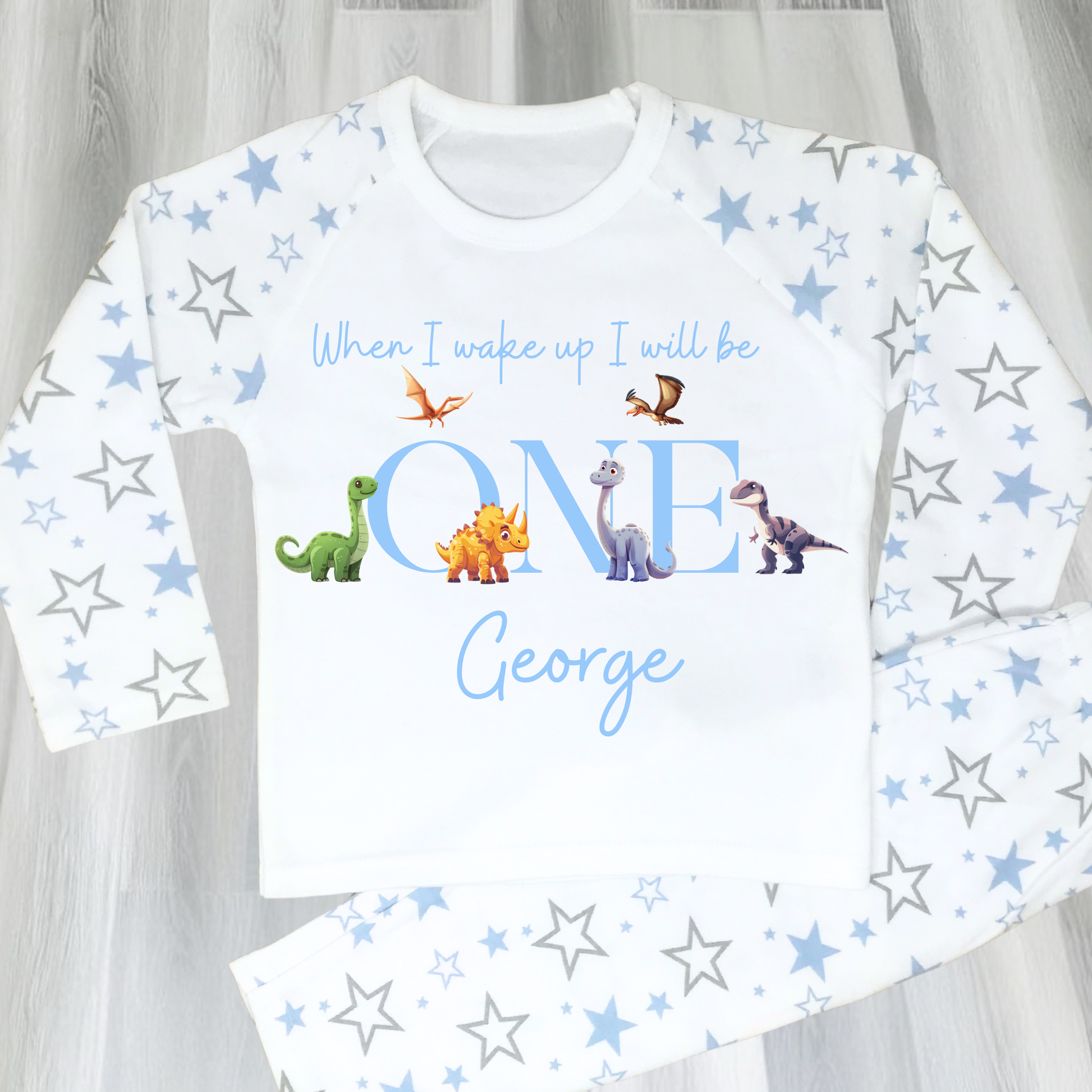 Dinosaur Birthday Pyjamas: A pair of toddler boys pyjamas with a dinosaur theme is displayed. The design features the phrase “When I Wake Up" accompanied by vibrant dinosaur graphics and the child's age. These two-piece pyjamas can be personalised with the boys name and age, creating a unique birthday outfit. Ideal for young dinosaur enthusiasts, these playful and colorful jammies make bedtime exciting and birthday mornings special.